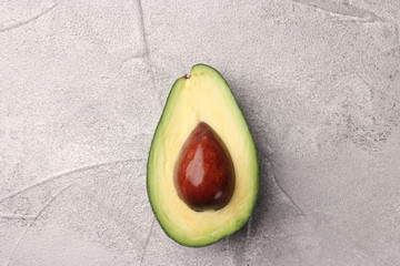 half avocado with seed on cement background top view