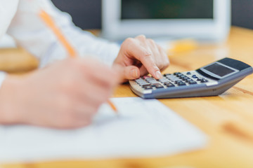 Closed a businessman holding a pencil holding a pencil running on a calculator to calculate the financial data of the report.