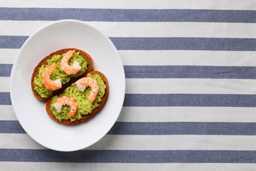 sandwich with avocado guacomole and srimp on plate