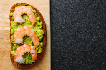 shrimp and guacamole with bread on dark background