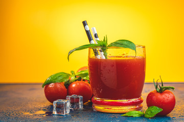 Red cocktail with tomato juice between tomatoes, fresh basil and ice