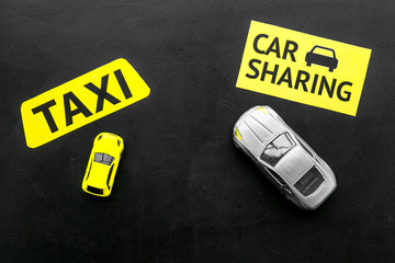 Carsharing vs taxi concept. Comparing carsharing system and taxi. Toy cars and text signs on black...