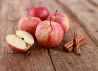 Red winter Apple with cinnamon sticks on rustic wooden table - close up