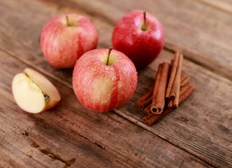 Red winter Apple with cinnamon sticks on rustic wooden table - close up