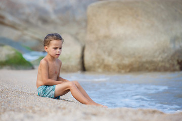 boy sitting on the sand by the sea