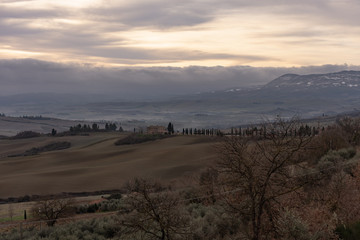 hills, meadows clouds, cypress trees and scattered trees, some buildings