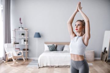 Fototapeta na wymiar Portrait of attractive young female with beautiful athletic body practicing yoga at home.