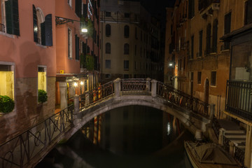 Obraz na płótnie Canvas Italy, Venice, a long bridge over a canal in a city at night