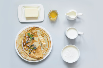Obraz na płótnie Canvas Crepes, thin pancakes on white plate. Pastel blue background. Top view. Set.