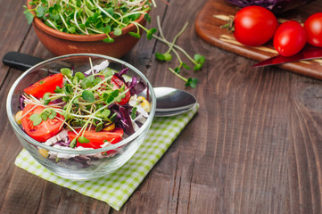Salad with radish sprouts near board with ingredients on rustic wooden background