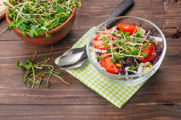 Salad with red cabbage, radish sprouts, corn and tomatoes in glass bowl