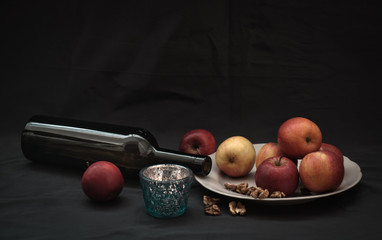 still life with apples, walnuts, candle and wine bottle