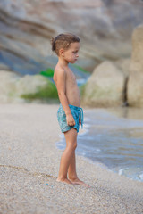 Fototapeta na wymiar boy standing on the sand by the sea