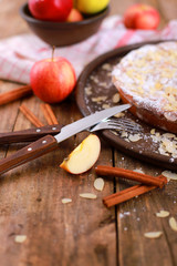 homemade apple pie - on a plate with fresh apples and cinnamon sticks on a rustic wooden table