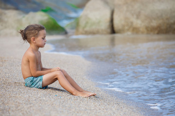 Fototapeta na wymiar boy sitting on the sand by the sea