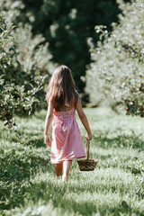 girl in pink dress in garden picking apples