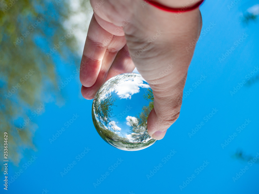 Wall mural An unrecognizable person with a crystal ball in his hand with a landscape reflection