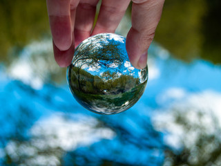 An unrecognizable person with a crystal ball in his hand with a landscape reflection