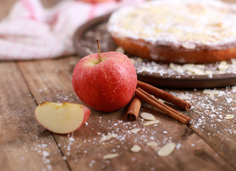 Apple pie - fresh apples and cinnamon sticks in front of a homemade apple pie on a rustic wooden...