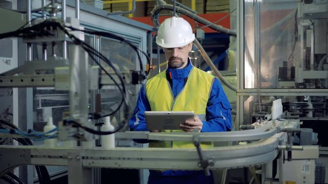 Male engineer is inspecting production of plastic containers