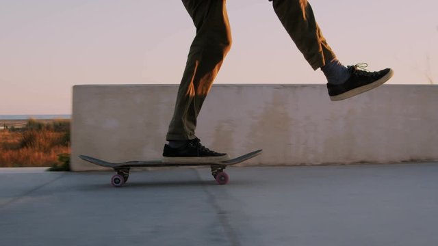 Close up of skateboarder ride in and out of frame, when riding through beautiful orange sunset on summer evening. Flow and chill, swaying with grace, practiced moves