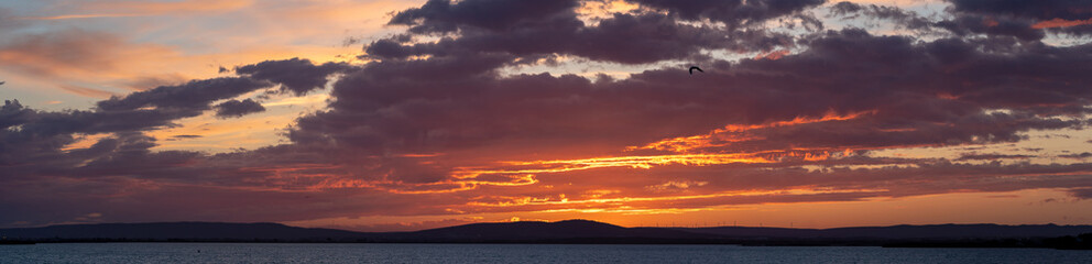 panorama avec coucher de soleil sur des montagnes avec lac en premier plan