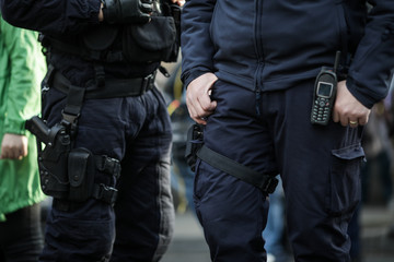 Details of the security kit of a riot police officer, including handcuffs, 9mm handgun, radio station and baton