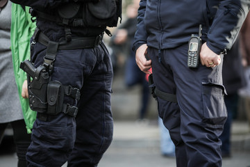 Details of the security kit of a riot police officer, including handcuffs, 9mm handgun, radio station and baton