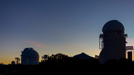 Fototapeta na wymiar Silhouetes of telescopes in a professional astronomical observatory at sunset waiting to observe the skies