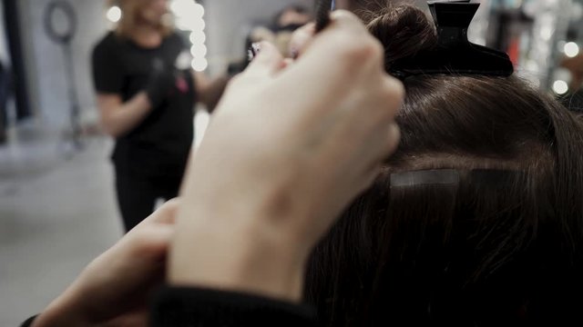 The hairdresser sticks the artificial hair to the real thing. The process of hair extension. 4K