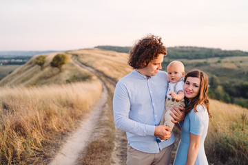 Young happy caucasian couple with little baby boy. Parents and son walking and having fun together. Mother and father playing with toddler outdoors. Family, parenthood, childhood, happiness concept.