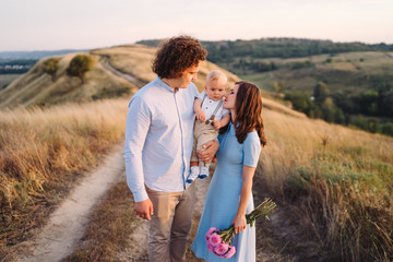 Young happy caucasian couple with little baby boy. Parents and son walking and having fun together. Mother and father playing with toddler outdoors. Family, parenthood, childhood, happiness concept.