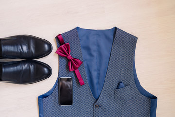 Wedding fashion for men. Top view of modern groom's outfit: leather shoes, bow tie, smart phone and...