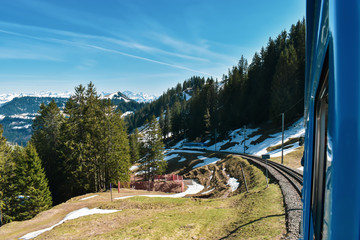Swiss mountain railways and spring panoramic view of snow-capped mountains in the Alps.