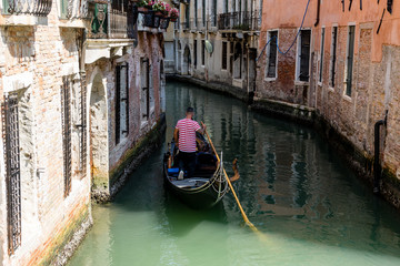Fototapeta na wymiar Italy, Venice, Gondolier navigating a gondola near San Moise on a canal