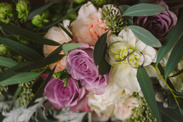 Beautiful bouquet of white and pink flowers with wedding rings on it