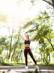 Athletic girl running in the nature. Female jogging on bridge at the park. Young woman stretching before run. Fitness model working out outdoor. Concept of healthy lifestyle.