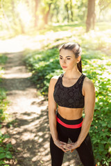 Athletic girl running in the nature. Female jogging on bridge at the park. Young woman stretching before run. Fitness model working out outdoor. Concept of healthy lifestyle.