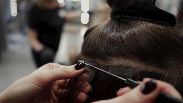 The hairdresser sticks the artificial hair to the real thing. The process of hair extension. 4K