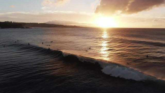 Aerial, surfers in Honokahua Bay, Hawaii at sunset