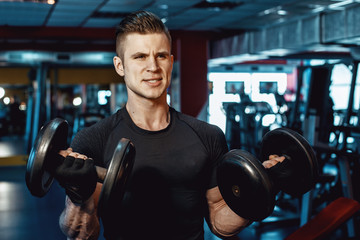 Muscular model sports young man exercising in gym with dumbbell. Portrait of sporty healthy strong muscle. Fitness trainer. Sport workout bodybuilding motivation concept.