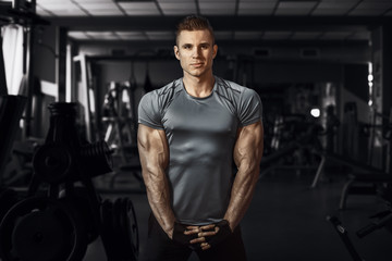 Fototapeta na wymiar Muscular model sports young man exercising in gym. Portrait of sporty healthy strong muscle. Fitness trainer. Sport workout bodybuilding motivation concept. Sexy torso.