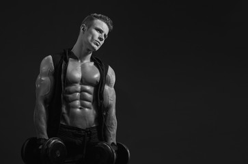 Fototapeta na wymiar Muscular model sports young man exercising with dumbbell on dark background. Portrait of sporty healthy strong muscle. Sport workout bodybuilding motivation concept. Sexy torso.