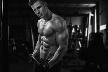 Fototapeta na wymiar Muscular model sports young man exercising in gym. Black and white portrait of strong muscle. Fitness trainer. Sport workout bodybuilding motivation concept. Sexy torso.