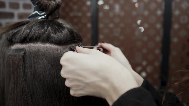 The hairdresser sticks the artificial hair to the real thing. The process of hair extension. 4K