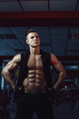 Fototapeta na wymiar Muscular model young man exercising in gym. Portrait of sporty strong muscle. Fitness trainer. Sport workout bodybuilding motivation concept. Sexy naked torso, six pack abs. Male flexing his muscles.