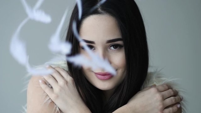 Close up portrait of woman open her eye with feathers falling down makeup and long eyelashes and free text space