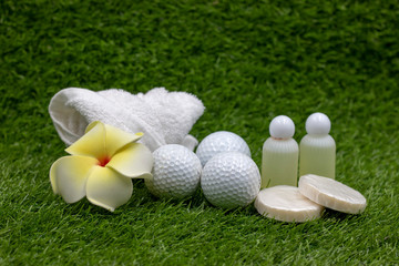 Golf ball with shampoo and soap and towel are on green grass in spa wellness