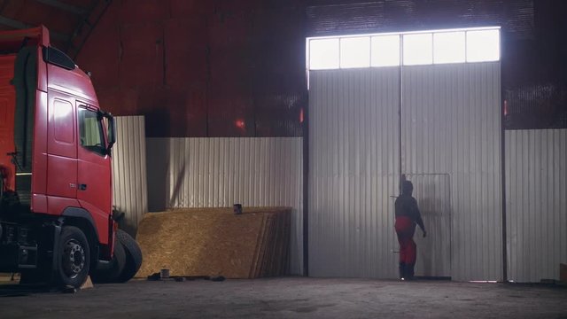Worker comes out of a large hangar with a truck