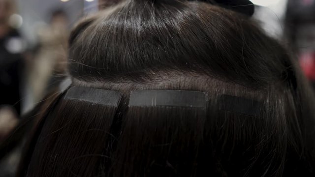 The hairdresser sticks the artificial hair to the real thing. The process of hair extension. 4K